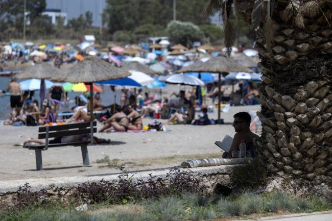 A man reads his book in the shadows of a tree at a beach, at Glyfada suburb, in Athens, Greece, Saturday, July 15, 2023. Temperatures reached up to 42 degrees Celsius in some parts of the country, amid a heat wave that co<em></em>ntinues to grip southern Europe. (AP Photo/Yorgos Karahalis)